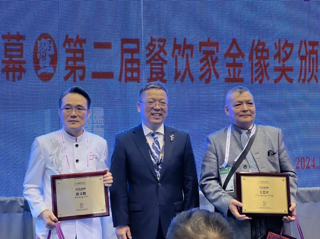 两位杰出餐饮家获奖者与颁奖嘉宾在第二届餐饮家金像奖颁奖典礼合影，展示奖牌。