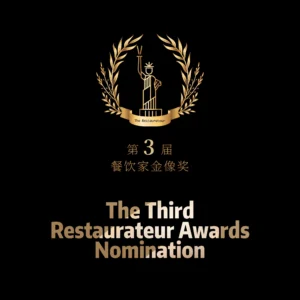 A black-background poster with a golden laurel wreath encircling a stylized Statue of Liberty holding a torch. Text includes "The Restaurateur" on a ribbon, Chinese characters "第3届 餐饮家金像奖" (3rd Restaurant Industry Golden Awards), and "The Third Restaurateur Awards Nomination" in gradient gold fonts. Symmetrical design conveys prestige for Chinese culinary excellence.