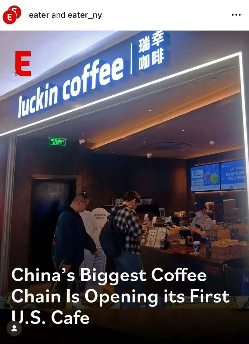 室内明亮的Luckin Coffee门店，蓝白色品牌招牌下，两名顾客在扫码自助下单，吧台后方员工佩戴口罩准备饮品，展示无收银员运营特色。