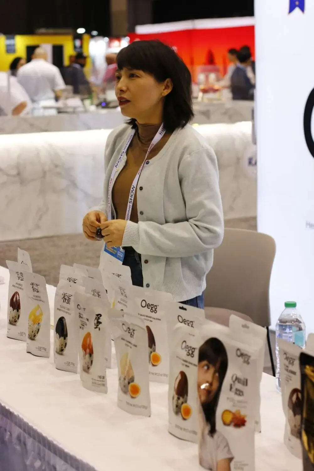 湖南零食品牌“零蛋”的负责人Lena站在一排零食产品展示台后面向观众做介绍