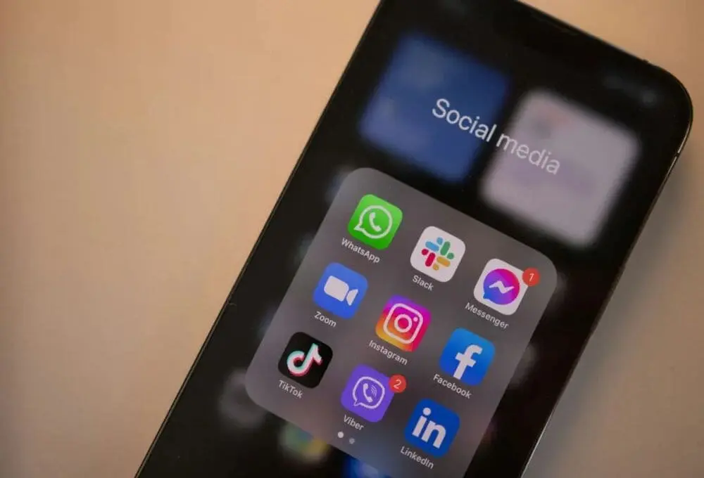 手机屏幕特写，密集排列的WhatsApp/Instagram等社交应用图标带未读提示。隐喻顾客即时分享行为场景。