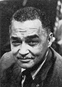 黑人男性肖像特写：底特律首位非裔市长科尔曼·杨（Coleman Young）戴领带，短发有皱纹，目光坚毅侧视，背景虚化。