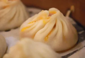蒸笼里一只煮熟的小笼包，流出金黄的汤汁