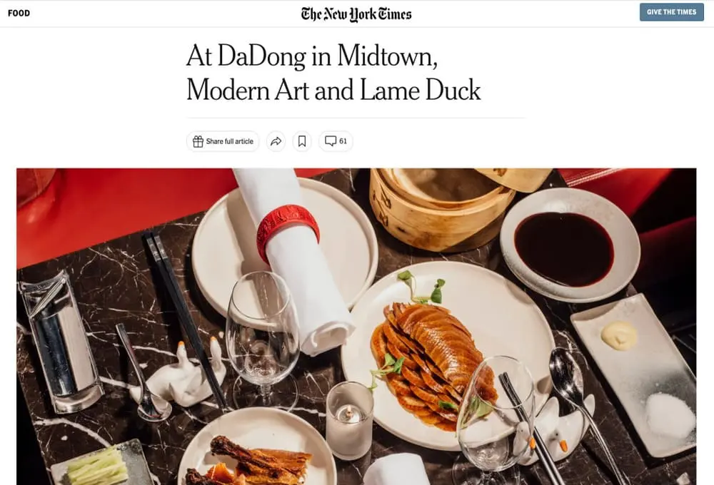 DaDong餐厅的桌面上摆放着精致的烤鸭、蘸酱、酒杯及特色摆件，尽显高雅餐饮氛围。