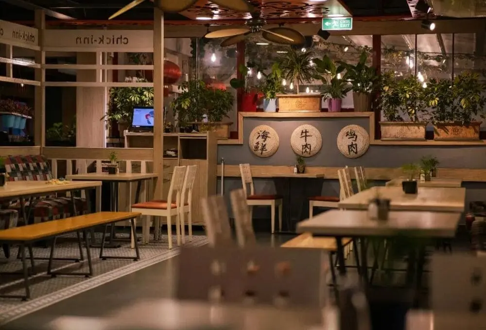 木质餐位搭配绿植装饰墙，墙面清晰标注“海鲜/牛肉/鸡肉”招牌品类，吧台设备齐全，展现舒适就餐环境与品类规划。