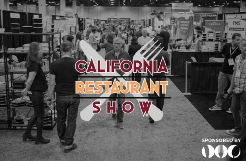 黑白摄影展现CRS展厅实况：中央悬挂红橙渐变立体字「CALIFORNIA RESTAURANT SHOW」，下方「SPONSORED BY FMS PARADA」标识。两侧展位陈列设备/食材，密集人流穿梭洽谈。全景呈现1200+供应商与12000+决策者规模，TOA亚洲展区集成于此产业资源中枢。
