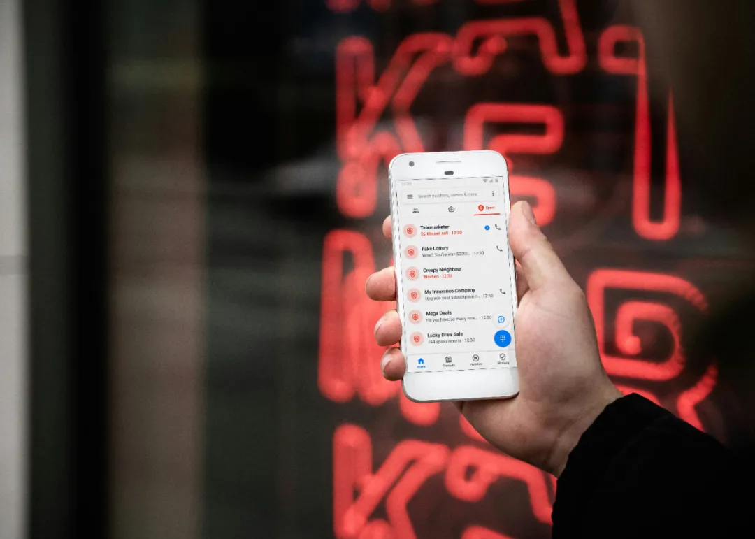 白色手机屏显"Telemarketer/Fake Lottery"等可疑记录，红蓝通话图标突出。背景霓虹光斑象征都市诈骗网络。骗子冒充Yelp/卫生局来电时显示类似界面（搭配紧急话术需警惕）。