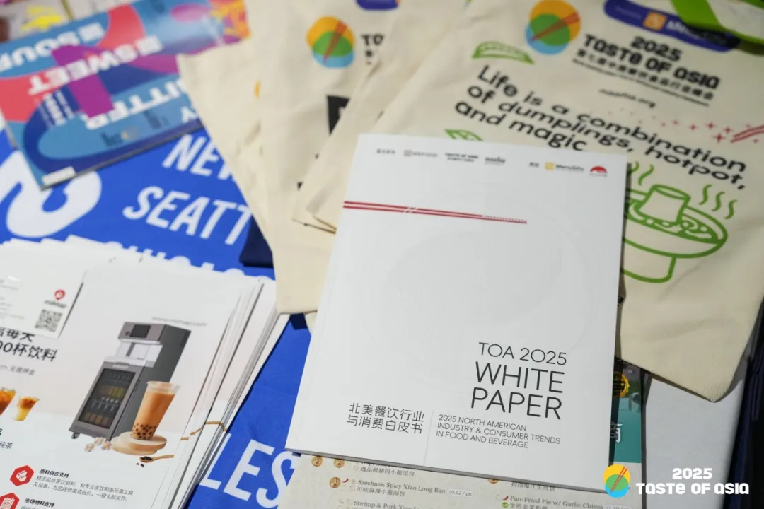 2025 TOA峰会核心成果：《北美餐饮行业与消费白皮书》米白封面居中，配火锅插画环保袋+西雅图站奶茶机资料卡。袋身标语"Life is dumplings, hotpot, and magic"呼应多元融合主题，体现峰会资源包实用价值。
