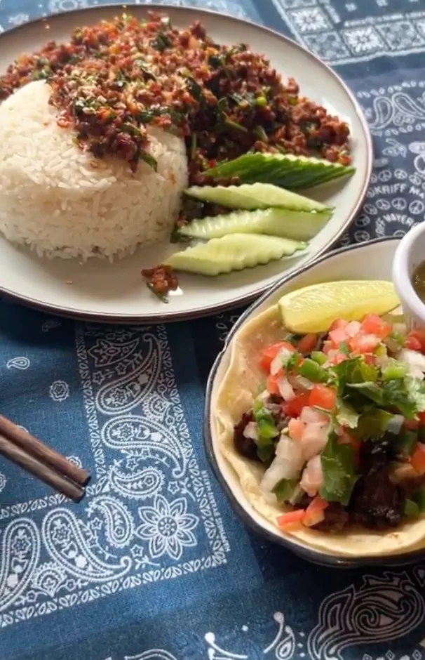 浅色瓷盘盛肉酱盖饭（白米饭+红棕肉酱+翠绿葱花），配青瓜片；右侧深色碗装墨西哥玉米饼（莎莎酱+柠檬角+蘸酱），置于佩斯利花纹桌布，左下可见木质筷子。