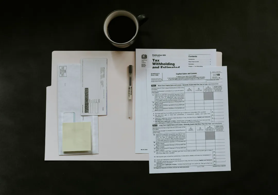 IRS税务表格（含EIN雇主识别号申请字段）、黄色便签与咖啡杯置于文件夹上。特写Schedule D税表强调餐厅需用EIN处理资本损益。