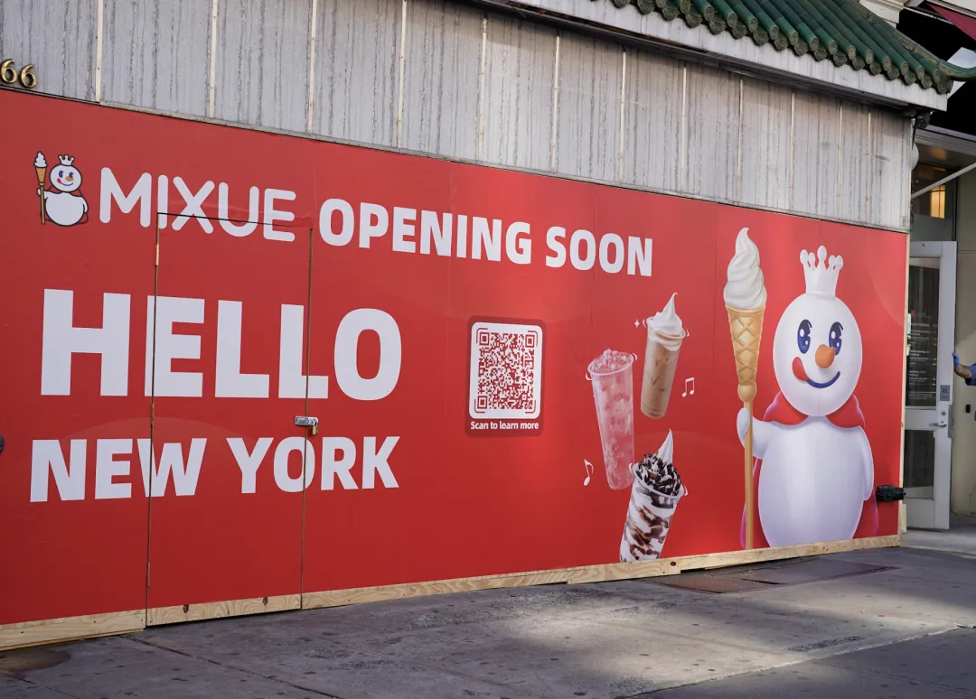 蜜雪冰城纽约店红色围挡，左侧雪人持火炬，上方“MIXUE OPENING SOON”“HELLO NEW YORK”，右侧饮品图案、二维码。