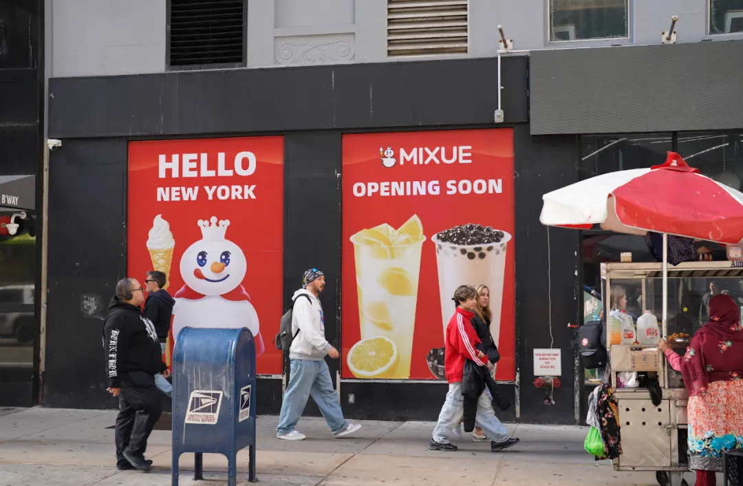 纽约街头建筑外墙红广告牌，左“HELLO NEW YORK”配雪人，右“MIXUE OPENING SOON”配饮品，行人、摊贩，多元城市景象。