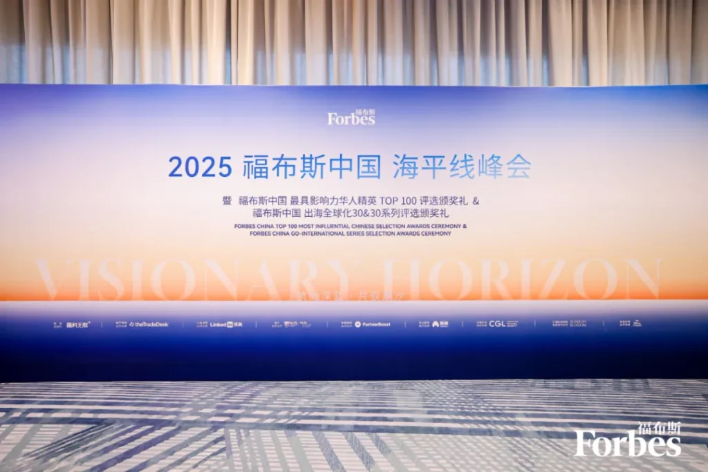 蓝橙渐变背景板印活动名称、“VISIONARY HORIZON”及合作方标识，地面有几何图案，右下角有Forbes标志。