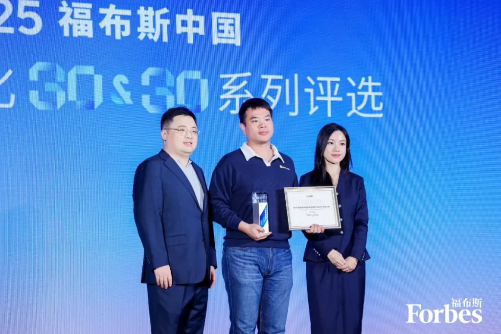 三人站舞台，中间持奖杯证书，背景屏显“25福布斯中国30 Under 30”及Forbes标志，氛围庄重。